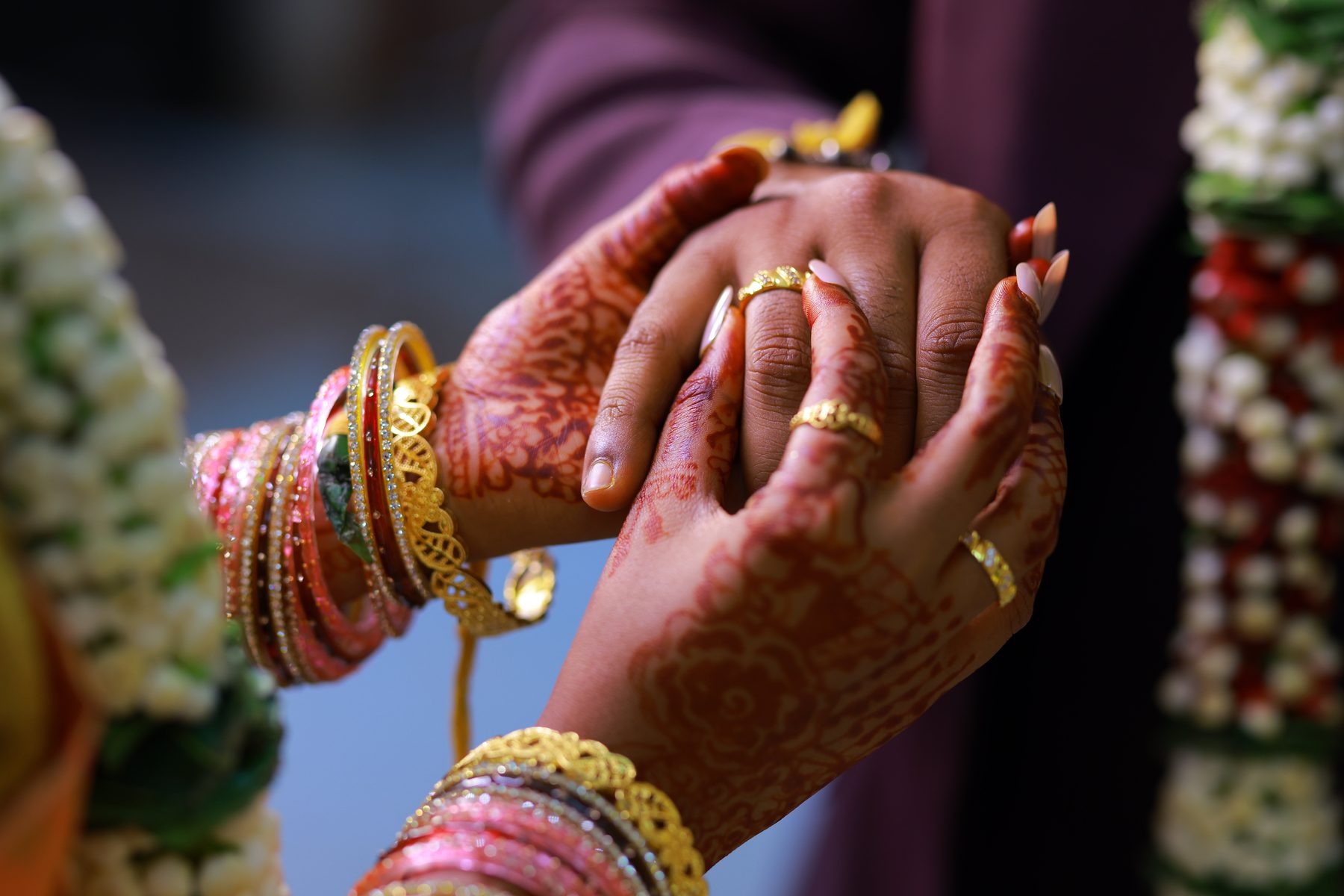 Lekha's mehndi-covered hands clasped together, rings on her fingers